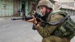 An Israeli soldier aims his weapon during clashes with Palestinian protesters in the city of al-Khalil, in the occupied West Bank.